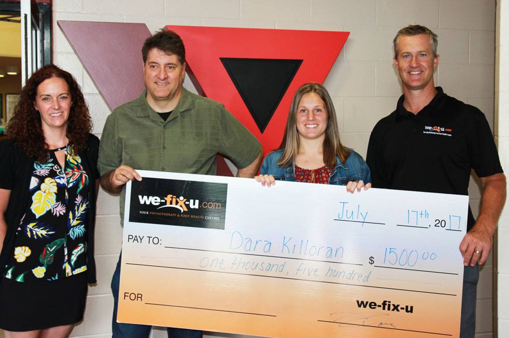 scholarship presentation four people holding a big cheque