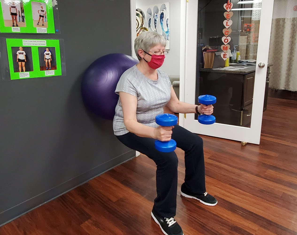 peterborough physiotherapy client exercising holding dumbbell with back against a medicine ball